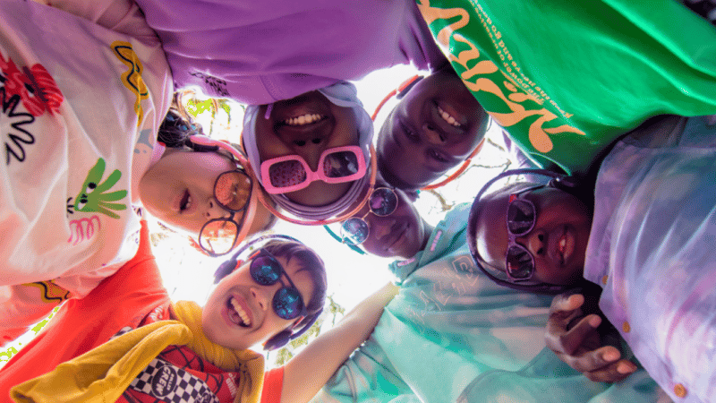 A group of young people gathered around the camera in colourful clothes